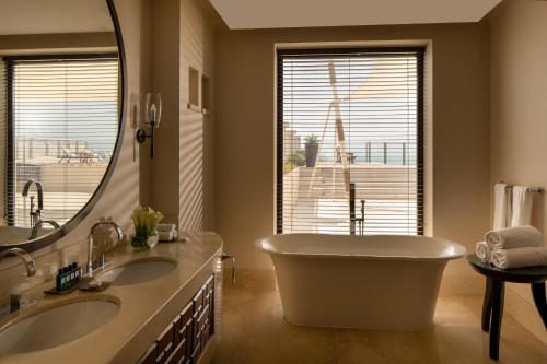 a bathroom with two sinks and a tub and a mirror at Sofitel Bahrain Zallaq Thalassa Sea & Spa in Manama