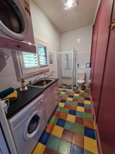a colorful bathroom with a sink and a washing machine at Back Creek Estate Cottage in Severnlea