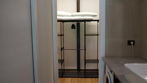 a bathroom with a sink and a shelf with towels at Ostello Loft La Fabbrica in Settimo Torinese