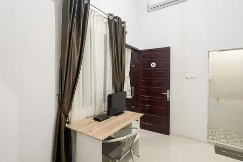 a room with a desk with a mirror and a door at An Nisa Homestay Syariah Aceh Mitra RedDoorz in Cotgirek