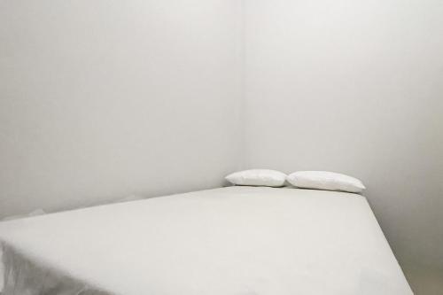 a white bed with two pillows on top of it at An Nisa Homestay Syariah Aceh Mitra RedDoorz in Cotgirek