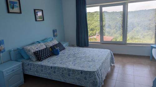 a bedroom with a bed and a large window at Guest House Chalakov in Sinemorets