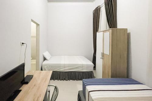a small room with two beds and a tv at An Nisa Homestay Syariah Aceh Mitra RedDoorz in Cotgirek