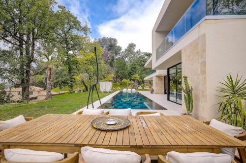 une terrasse avec une table et des chaises en bois ainsi qu'une piscine dans l'établissement Luxueuse Villa californienne à Opio, à Opio