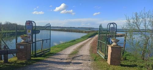 a gate on a path next to a river at Casa Vacanze Nel Delta del Po in Taglio di Po