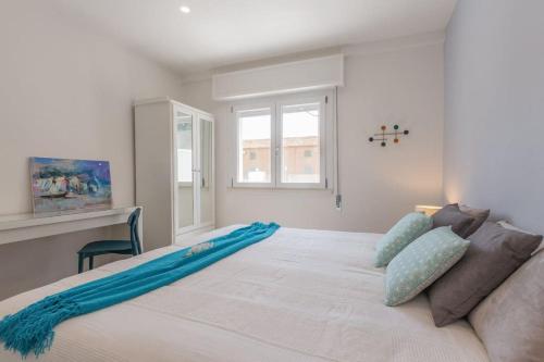 a bedroom with a large white bed with blue pillows at Villino in centro con cortile interno, wifi e aria condizionata in Codigoro