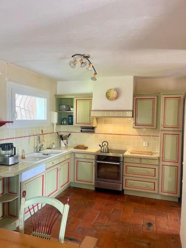 une cuisine avec des armoires blanches, un évier et une cuisinière dans l'établissement Villa paisible vue panoramique, au Lavandou