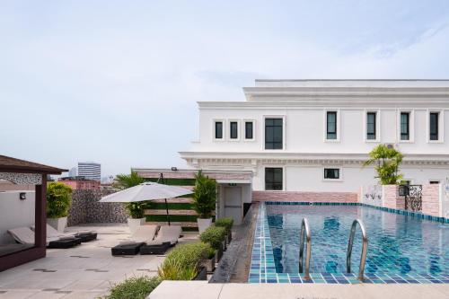 a swimming pool in front of a white building at Syama Hana Executive Apartments Thonglor in Bangkok