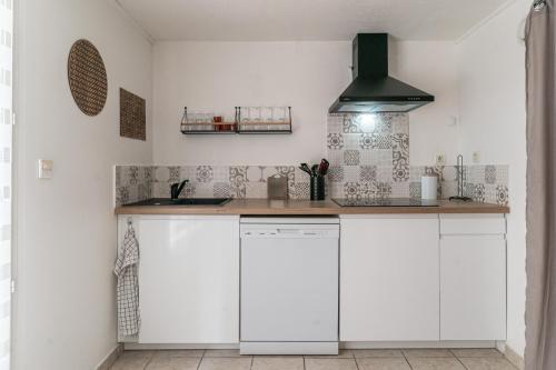 une cuisine avec des armoires blanches et un comptoir dans l'établissement Le Midi - duplex climatisé - proche plage, à La Ciotat