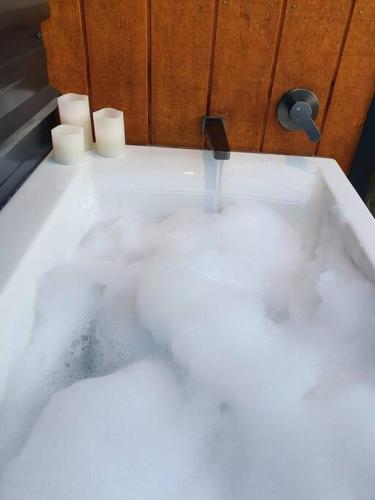 a white bath tub with water coming out of it at Cass Bay Retreat with Outdoor Bath Christchurch in  Lyttelton