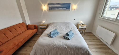 une chambre avec un canapé et deux oreillers bleus sur un lit dans l'établissement Grand Pavois - Appartement de standing - Vue mer -, à Les Sables-dʼOlonne