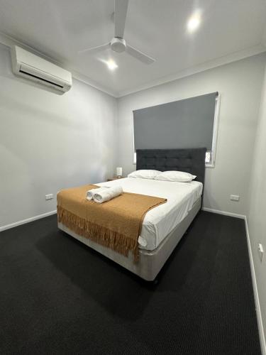 Holiday Home at Golf Course Townsville في تاونزفيل: غرفة نوم بسرير كبير في غرفة بيضاء