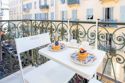 une table blanche avec deux tasses et des cupcakes sur un balcon dans l'établissement #13 Orange suite AC Wifi Balcony 3mins walk sea front, à Nice