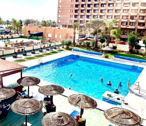 a large swimming pool with umbrellas and people in it at PYR Private Apartment SUNNY pool SIDE in Fuengirola