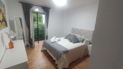 a white bedroom with a bed and a window at La casa de mayfer in Benamahoma