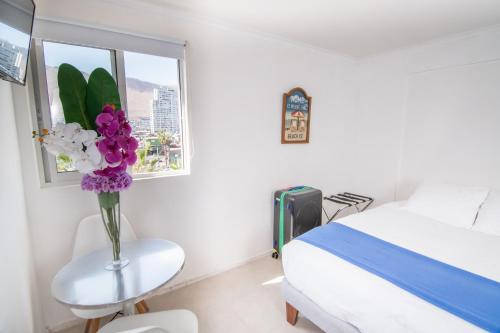a white room with a bed and a vase of flowers at Playa Hotel - Cavancha in Iquique