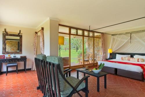 een slaapkamer met een bed, een bureau en stoelen bij Muthu Keekorok Lodge, Maasai Mara, Narok in Keekorok