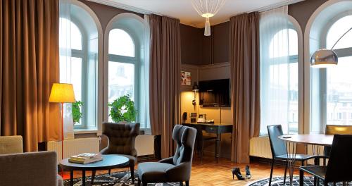 a living room with windows and a table and chairs at Scandic Grand Central in Stockholm