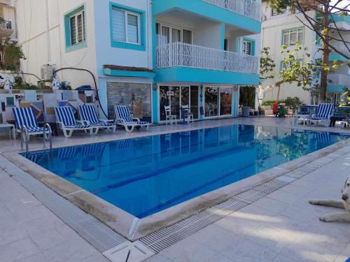 une piscine avec des chaises bleues et un bâtiment dans l'établissement ASIA APART HOTEL, à Kusadası