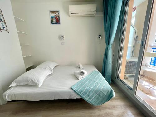 un petit lit dans une chambre avec une fenêtre dans l'établissement Le Rivage, joli appartement à 200 m des plages, à Menton