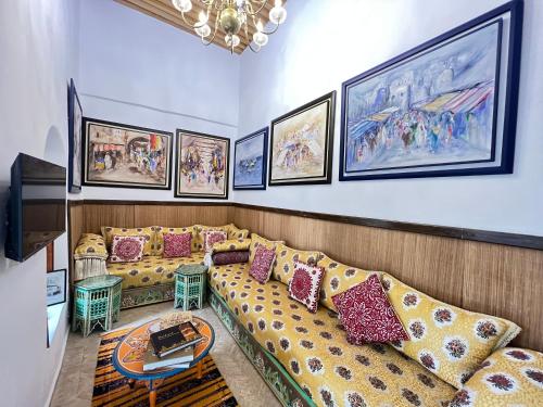 a living room with a couch and paintings on the wall at Dar Mounia in Rabat