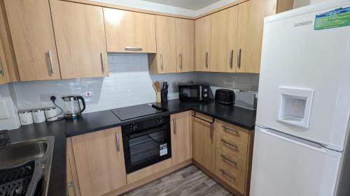 a kitchen with wooden cabinets and a white refrigerator at 2-Bed Riverside Stay - Sleeps 6 & Pets Ok in Greenhithe