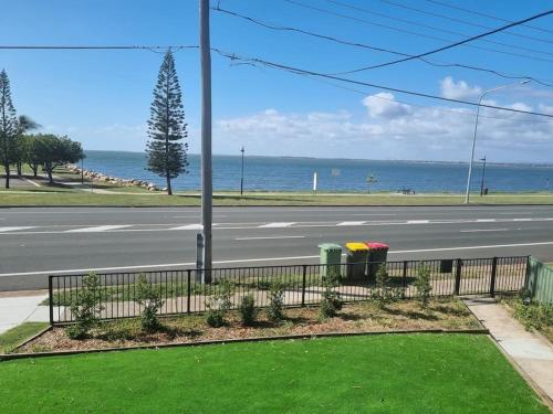 an empty street with a fence and green grass at Vandy Beach Cottage in Clontarf