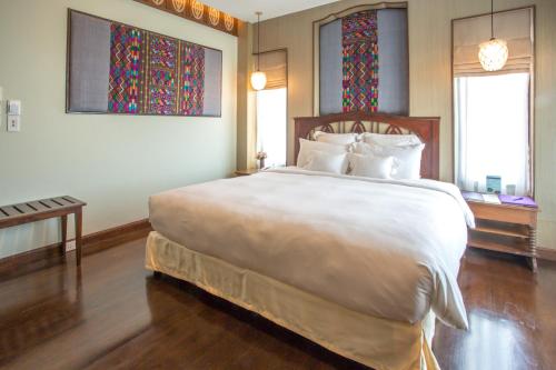 a bedroom with a large white bed and stained glass windows at Chankam Boutique Hotel in Chiang Mai
