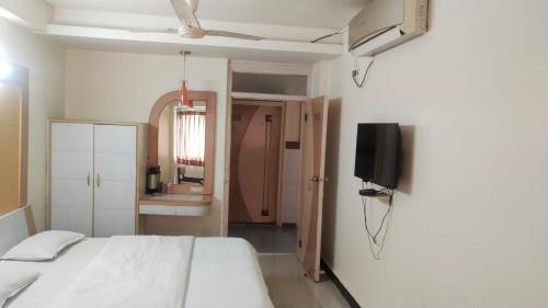 a bedroom with a bed and a tv on a wall at Hotel Vaishali in Nashik