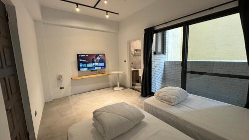a bedroom with two beds and a flat screen tv at Tianshe Xiangsui B&B in Hualien City