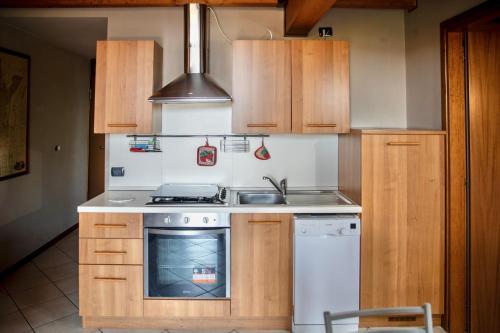 a kitchen with wooden cabinets and a stove and a sink at La casa di Monica con piscina e terrazza in Moniga