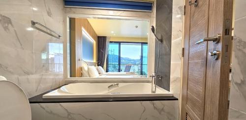 een badkamer met een bad en een grote spiegel bij Dome Kata Resort in Kata Beach