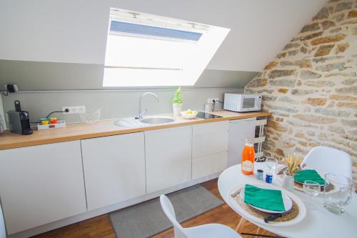 une cuisine avec un évier et une table avec des chaises dans l'établissement -PICCO BIANCO-Studio entierement renove-Concarneau, à Concarneau