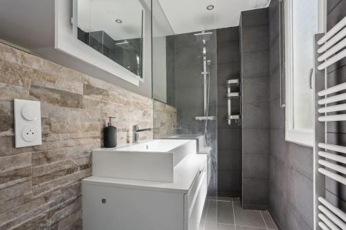 une salle de bain avec un lavabo blanc et une douche dans l'établissement 9-minute walk from La Défense - 1 bedroom, à Courbevoie