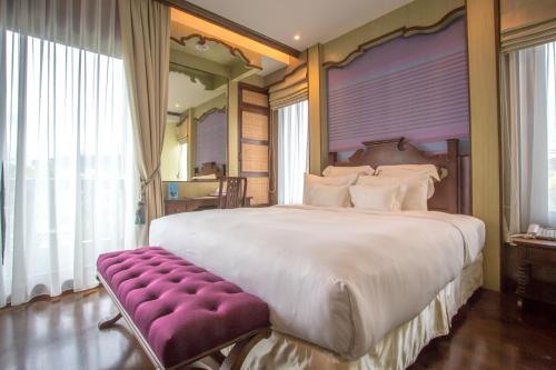 a large bedroom with a large bed and a purple bench at Chankam Boutique Hotel in Chiang Mai