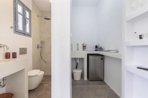 a white bathroom with a toilet and a sink at Aitheras Luxury Suites in Protorgia