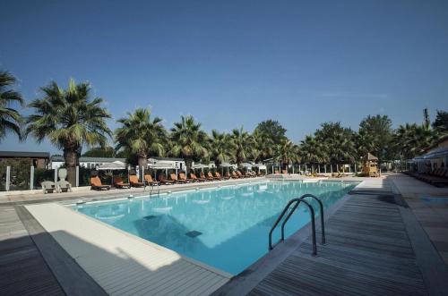 une grande piscine avec chaises et palmiers dans l'établissement mobil home climatisé, à Grimaud