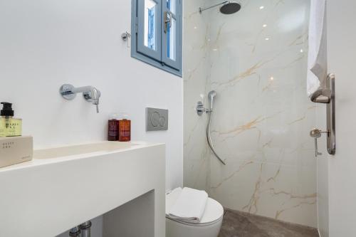 a bathroom with a shower with a toilet and a sink at Aitheras Luxury Suites in Protorgia
