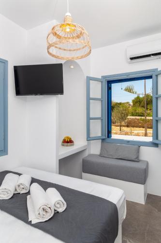 a bedroom with a bed and a window with a chair at Aitheras Luxury Suites in Protorgia