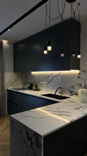 a kitchen with black cabinets and a marble counter top at The Loft Luxury Apartment in Shkodër