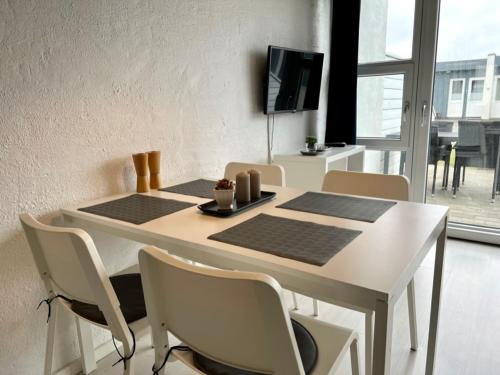 a dining room table with chairs and a tv at Agger Tange Feriecenter lejligheder - 100 m fra Vesterhavet in Vestervig