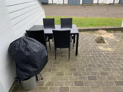 a black table and chairs with a trash can next to it at Agger Tange Feriecenter lejligheder - 100 m fra Vesterhavet in Vestervig