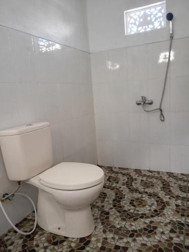 a bathroom with a white toilet and a shower at Batur Volcano Cottage in Kubupenlokan