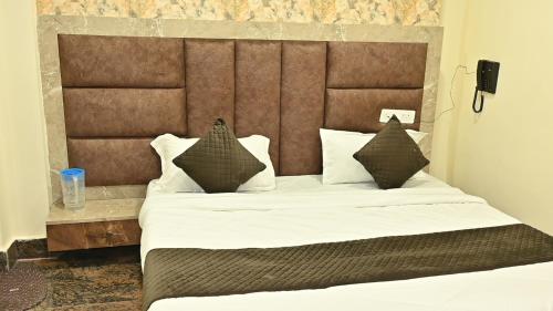 una habitación con una cama grande con sábanas y almohadas blancas en Hotel Kaka Inn, en Ajmer