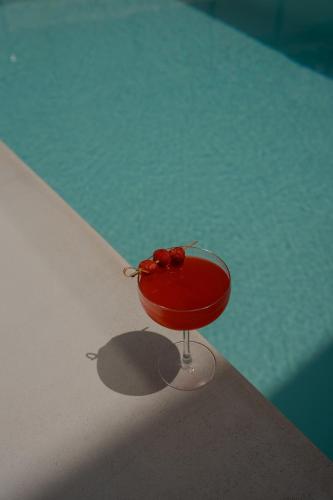 a red drink in a martini glass next to a pool at Athos Guesthouse in Stalos