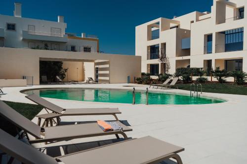 a swimming pool with chaise lounges next to a building at Casas do Forte Wood 6pax Piscina Privativa by Portugal Hideaway in Tavira