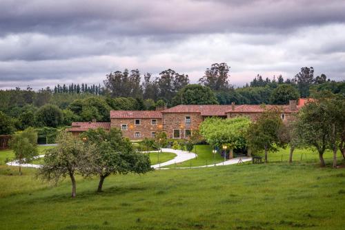 a large brick building in a field with trees at Pazo Santa María in Arzúa
