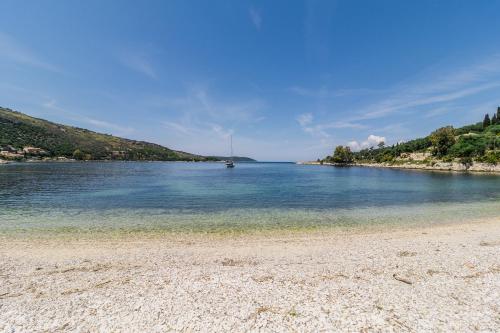 a beach with a boat in a large body of water at Lena Kassiopi Apartments in Kassiopi