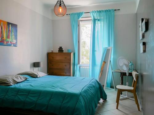 - une chambre avec un lit bleu, un bureau et une fenêtre dans l'établissement Grand duplex de charme en pleine campagne, à Hyères