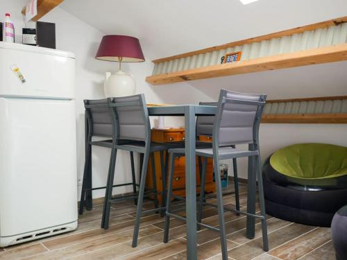 La cuisine est équipée d'une table, de deux chaises et d'un réfrigérateur. dans l'établissement Grand duplex de charme en pleine campagne, à Hyères